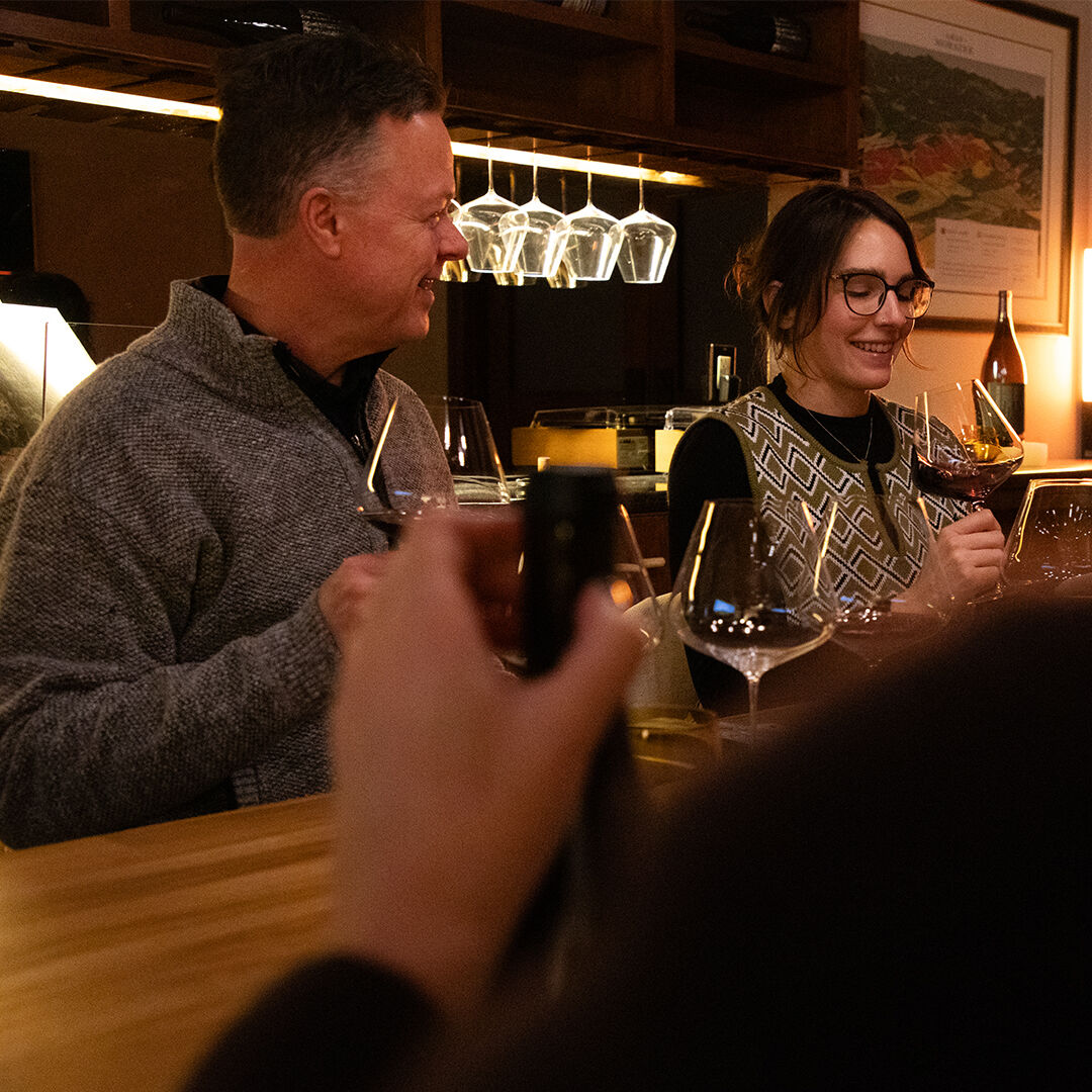 Man and woman laughing while enjoying glass of red wine in Zena Crown Tasting Experience. Man and woman laughing while enjoying glass of red wine in Zena Crown Tasting Experience.